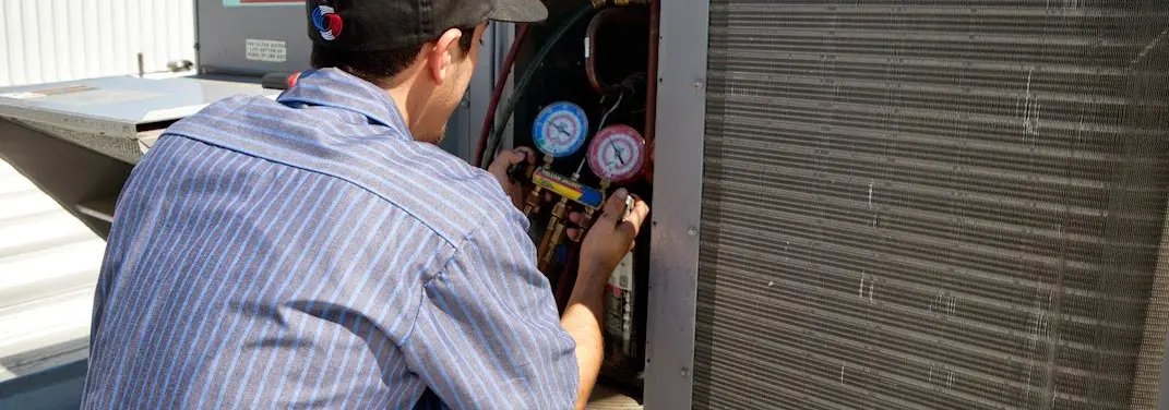 HVAC technician servicing a condenser unit in Ware